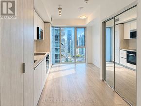 Toronto (Waterfront Communities) condo for rent - A modern kitchen with wooden floors and a large window overlooking the city.