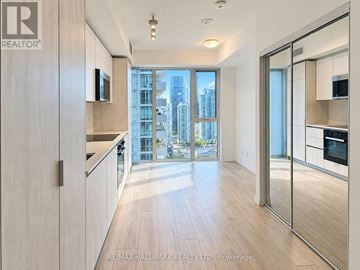 Toronto (Waterfront Communities) condo for rent - A modern kitchen with wooden floors and a large window overlooking the city.