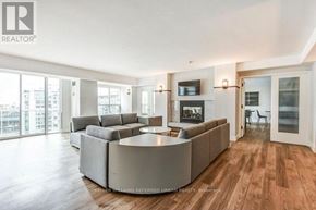 Toronto (Moss Park) condo for rent - A spacious living room with a large grey sofa and a television on the wall.