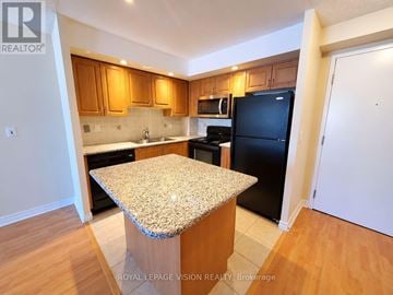 Markham (Unionville) condo for rent - A kitchen with a granite countertop and wooden cabinets.