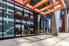 Toronto (Waterfront Communities) condo for rent - A modern building entrance with glass doors and a large orange structure above.