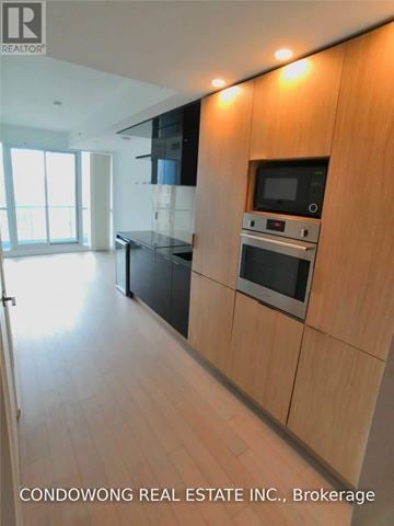 Toronto (Bay Street Corridor) condo for rent - A modern kitchen with wooden cabinets and a microwave.