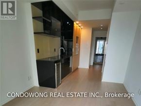 Toronto (Bay Street Corridor) condo for rent - A kitchen with black appliances and a wooden floor.