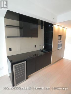 Toronto (Bay Street Corridor) condo for rent - A modern kitchen with dark brown cabinets and a black fridge.