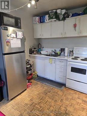 Toronto (Dufferin Grove) multi-family for rent - A kitchen with a refrigerator, oven, and cabinets.