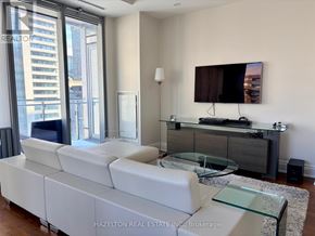 Toronto (Annex) condo for rent - A modern living room with a white sofa and a glass coffee table.