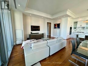 Toronto (Annex) condo for rent - A modern living room with a white sofa set and a glass table.