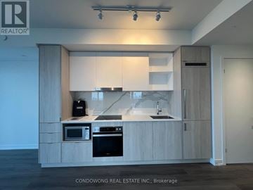 Toronto (Waterfront Communities) condo for rent - A modern kitchen with wooden cabinets and appliances.