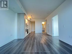 Toronto (Waterfront Communities) condo for rent - A spacious room with wooden flooring and white walls.