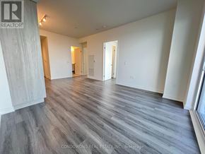 Toronto (Waterfront Communities) condo for rent - A spacious room with wood flooring and white walls, part of a real estate brokerage.