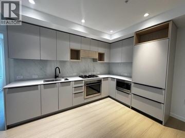 Port Moody apartment for rent - A modern kitchen with a wooden floor and grey cabinets.