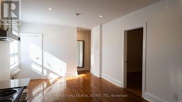 Toronto (Wychwood) multi-family for rent - A spacious, well-lit kitchen with a stove top oven and a doorway leading to another room.