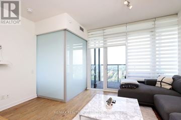 Toronto (Mimico) condo for rent - A living room with a grey couch and a glass door.
