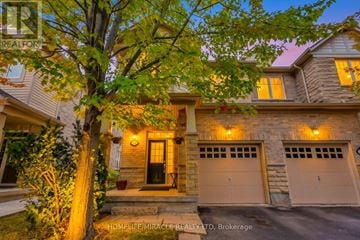 Caledon townhouse for rent - A house with a front yard and garage doors.