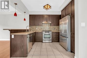 Caledon townhouse for rent - A kitchen with brown cabinets and a tile backsplash.