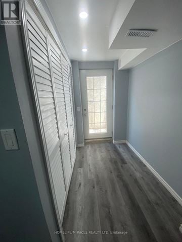 Brampton (Heart Lake East) apartment for rent - A hallway with wood floors and white walls leading to a door with a window.