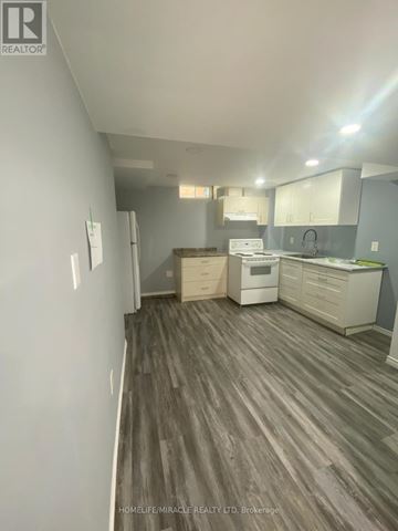 Brampton (Heart Lake East) apartment for rent - A real estate listing photo of a kitchen and living room with wood flooring.