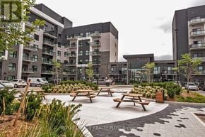 Oakville (Go Glenorchy) condo for rent - A modern apartment complex with a courtyard and picnic tables.