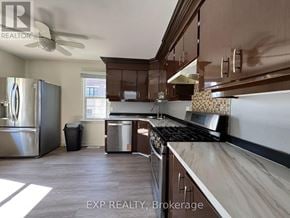 Richmond Hill (Oak Ridges Lake Wilcox) apartment for rent - A kitchen with a stainless steel refrigerator, a black stove top, and wooden cabinets.