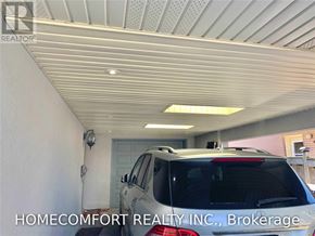 Toronto (Willowridge-Martingrove-Richview) apartment for rent - A car is parked in a garage with the text "HOMECOMFORT REALTY INC., Brokerage" on the wall.