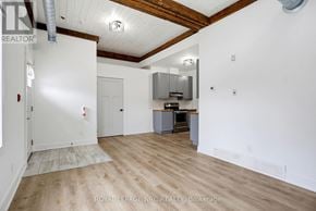 Fort Erie (Crystal Beach) multi-family for rent - A room with wooden floors and white walls, with a kitchen area in the background.