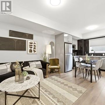 Niagara Falls (Arad/Fallsview) townhouse for rent - A modern living room with a black sofa, a coffee table, and a dining area with a table and chairs.