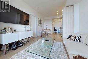 Toronto (Niagara) condo for rent - A modern living room with a glass coffee table and a white couch.