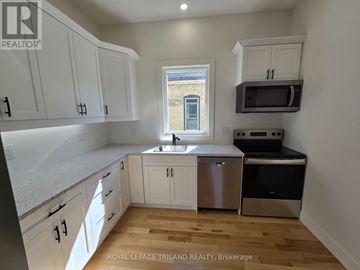 St. Thomas triplex for rent - A kitchen with white cabinets and a window.