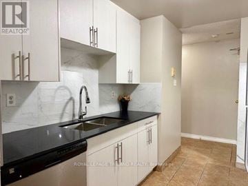 London East (East H) condo for rent - A kitchen with white cabinets and black countertops.