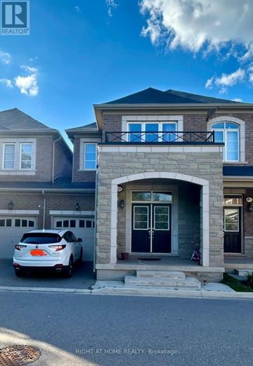 Oakville (Go Glenorchy) townhouse for rent - A white car is parked in front of a house with a stone archway entrance.