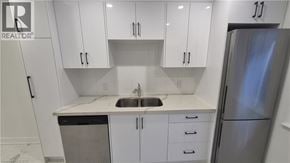 Brantford apartment for rent - A kitchen with white cabinets and a stainless steel refrigerator.