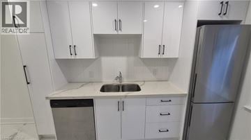 Brantford apartment for rent - A kitchen with white cabinets and a stainless steel refrigerator.