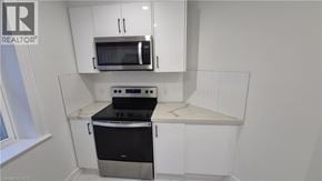 Brantford apartment for rent - A kitchen with white cabinets and a black stove top oven.
