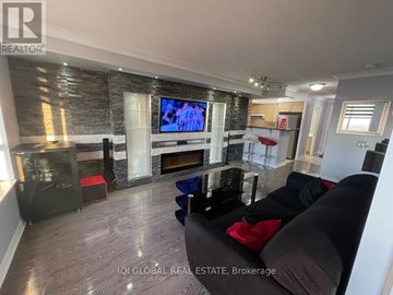 Toronto (West Humber-Clairville) condo for rent - A living room with a stone fireplace and a flat screen TV mounted above it.