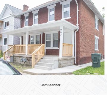 Columbus apartment for rent - A red brick house with a white porch and a green trash can in front.