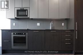 Toronto (Church-Yonge Corridor) condo for rent - A modern kitchen with dark wood cabinets and a stainless steel microwave above the oven.