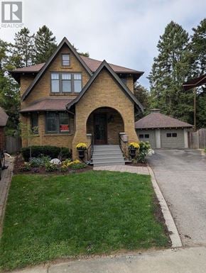 London East (East B) apartment for rent - A house with a brown roof and a front yard with a lawn and flowers.