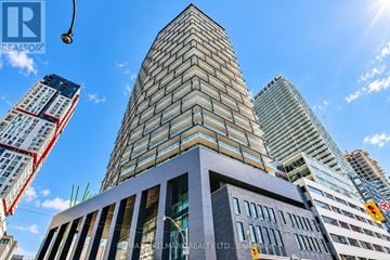 Toronto (Waterfront Communities) condo for rent - A tall building with a glass facade stands in front of other skyscrapers.