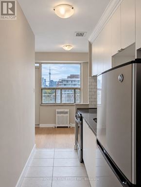 Toronto (Annex) condo for rent - A kitchen with white appliances and a window overlooking a cityscape.