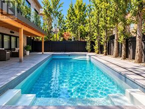 Toronto (Leaside) apartment for rent - A swimming pool in a backyard with a wooden deck and a black fence.