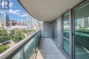 Toronto (Waterfront Communities) condo for rent - A balcony with glass railings overlooks a city skyline.