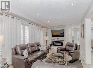 Brampton (Fletcher's Meadow) apartment for rent - A living room with a brown leather couch and a glass coffee table.