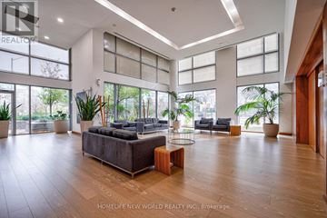 Mississauga (City Centre) condo for rent - A spacious living room with a large grey sofa and wooden flooring.