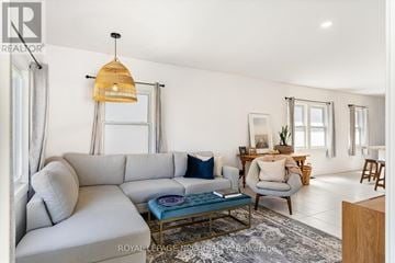 St. Catharines (Port Dalhousie) apartment for rent - A living room with a grey sofa and a woven hanging light fixture.