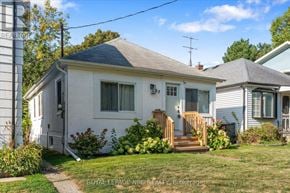St. Catharines (Port Dalhousie) apartment for rent - A white house with a grey roof and a wooden staircase leading to the front door.