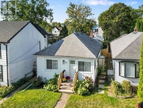 St. Catharines (Port Dalhousie) apartment for rent - A white house with a grey roof is surrounded by greenery and other houses.