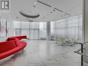Toronto (Waterfront Communities) condo for rent - A spacious living room with a red sofa and white chairs.