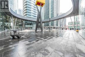 Toronto (Waterfront Communities) condo for rent - A wet sidewalk in front of a building with a yellow sign.