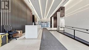 Toronto (Moss Park) condo for rent - A modern office lobby with a white reception desk and a black and white striped wall.