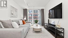 Toronto (Moss Park) condo for rent - A living room with a grey couch, a coffee table, and a flat screen TV mounted on the wall.